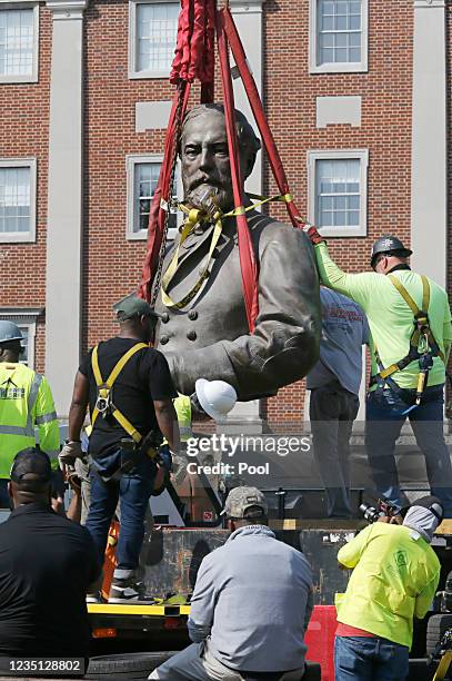 The top half of the statue of Confederate General Robert E. Lee is moved by a crane after being cut from the rest of the sculpture during removal...