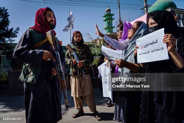 Taliban fighters try to stop the advance of protesters marching through the Dashti-E-Barchi neighborhood, a day after the Taliban announced their new...