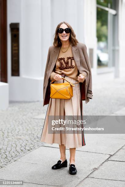 Influencer Annette Weber, wearing a pleated skirt by Gucci , a camel colored Cashmere Pullover by Max Mara, black loafers by Loro Piana and a orange...