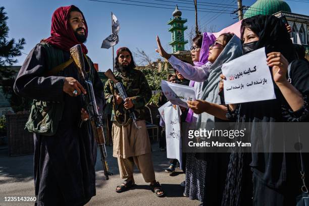 Taliban fighters try to stop the advance of protesters marching through the Dashti-E-Barchi neighborhood, a day after the Taliban announced their new...