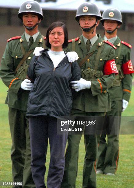 Police guard a woman prisoner during an execution rally at a stadium in Kunming, capital of China's southwestern Yunnan province, 26 June 2001. China...