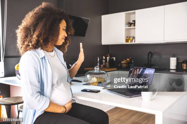 vrouw die van huis op laptop in haar heldere keuken werkt - pregnant women greeting stockfoto's en -beelden