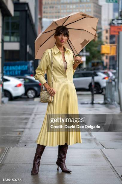 Katya Tolstova is seen wearing a dress by Jonathan Simkhai, Valentine Purse, boots by Raye and an umbrella by Moschino while departing the Bevza...