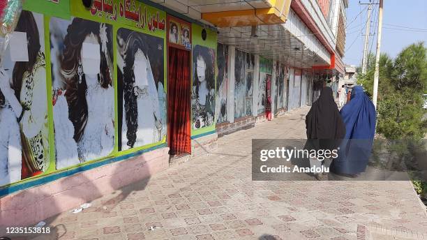 Afghan beauticians paint over large photos of women on the doors of beauty salons after Taliban control across the country in Nangarhar, Afghanistan,...