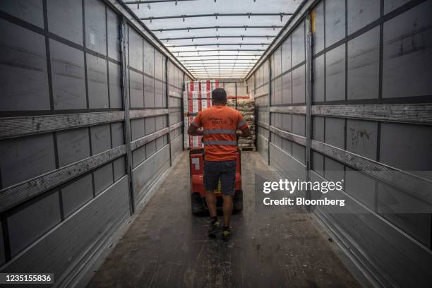 Worker uses a low lift pallet truck to unload goods from a truck in the loading bay at the Mercabarna food wholesale complex in Barcelona, Spain, on...