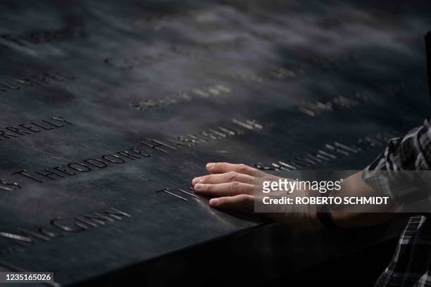 Woman runs her hand over the name of a NYC firefighter during a visit to the National 9/11 Memorial and Museum on September 10 one day before the...