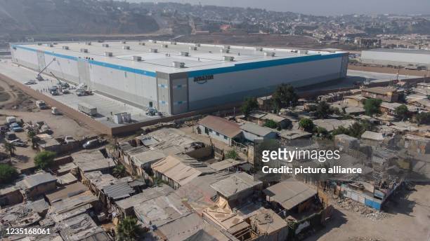 September 2021, Mexico, Tijuana: Amazon's new warehouse stands surrounded by a wall next to a poorer neighborhood. Photo: Stringer/dpa