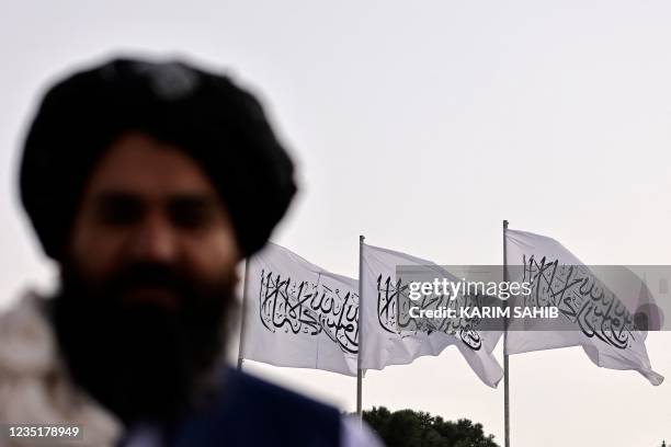 Taliban fighter is pictured against the backdrop of Taliban flags installed at the Hamid Karzai International Airport in Kabul on September 11, 2021.