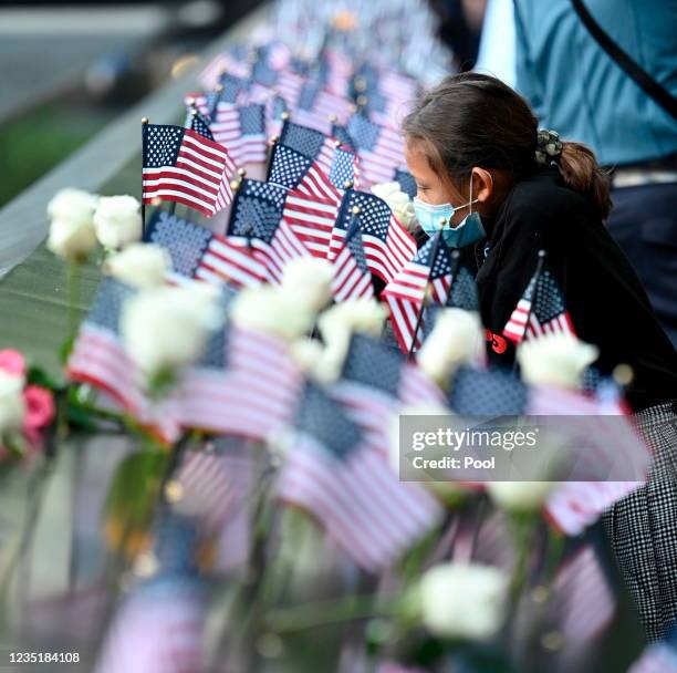 Family member at the reflecting pool places a flag during a ceremony at the National September 11 Memorial & Museum commemorating the 20th...