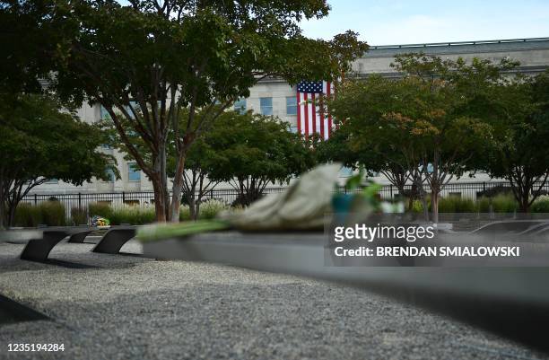 Flag is seen on the facade of the Pentagon as flowers are left at the National 9/11 Pentagon Memorial during a wreath-laying ceremony in Virginia on...