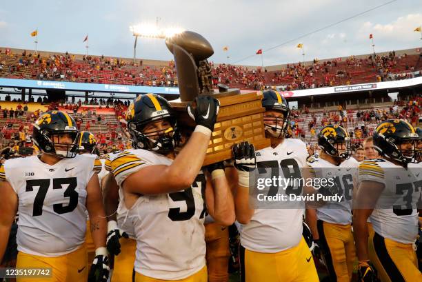Defensive lineman Zach VanValkenburg of the Iowa Hawkeyes and offensive lineman Jack Plumb of the Iowa Hawkeyes carry the Cy-Hawk Trophy off the...