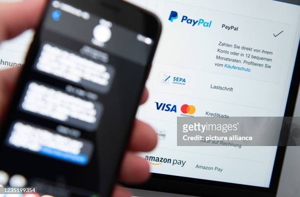 September 2021, Baden-Wuerttemberg, Rottweil: A man holds his smartphone for two-factor authentication while various payment methods are shown on the...