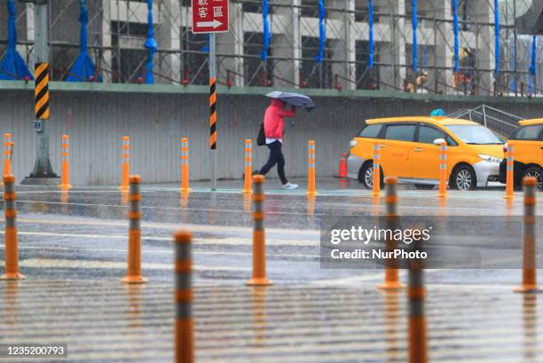 People with umbrellas walk in strong rains and winds in Keelung where boats are docked at, as Typhoon Chanthu bringing torrential rains and damaging...