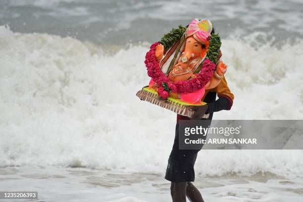 Volunteer carries an idol of the elephant-headed Hindu god Ganesha for an immersion in the Bay of Bengal on the third day of the ten-day-long Ganesh...