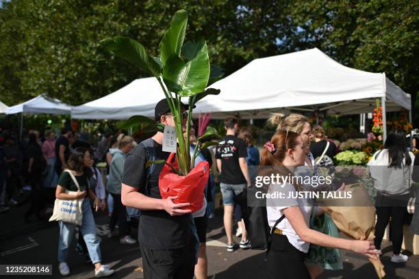 People carry their flowers and plants at Columbia Road flower market in east London on September 12, 2021. The weekly flower market takes place every...