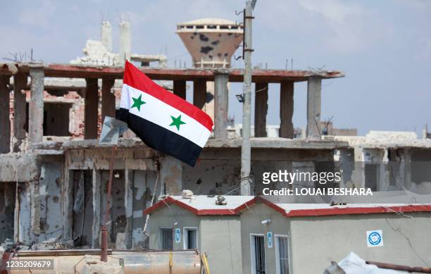 Picture taken during a tour organized by the Syrian Ministry of Information shows a Syrian flag atop damaged buildings in the district of Daraa...