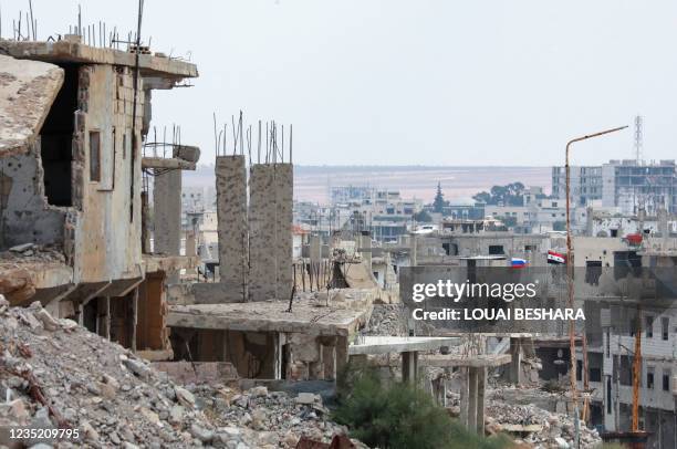 Picture taken during a tour organized by the Syrian Ministry of Information shows flags of Russia and Syria atop a damaged building in the district...