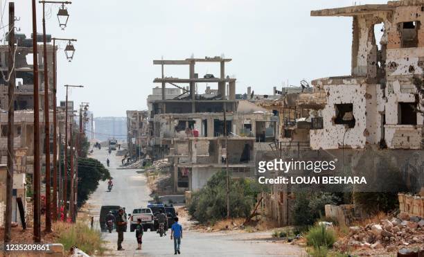 Picture taken during a tour organized by the Syrian Ministry of Information shows Security forces vehicles and locals on motorbikes in the district...