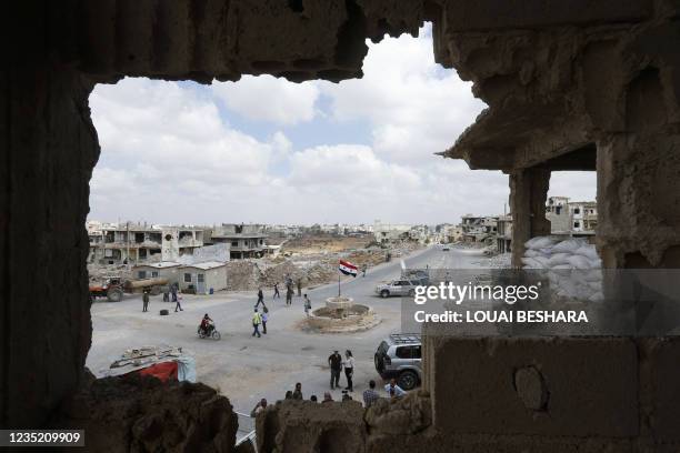 Picture taken during a tour organized by the Syrian Ministry of Information shows people and journalists at a damaged roundabout in the district of...