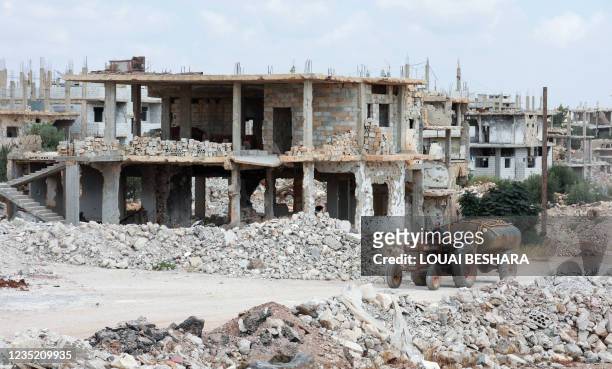 Picture taken during a tour organized by the Syrian Ministry of Information shows a man driving a water tank truck past damaged buildings in the...