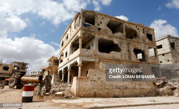 Picture taken during a tour organised by the Syrian Ministry of Information shows Syrian soldiers standing next to a damaged building in the district...