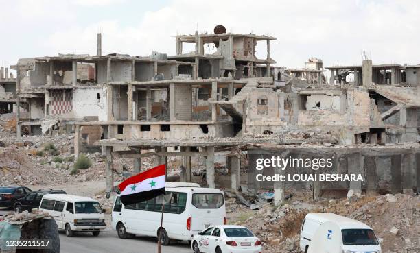 Picture taken during a tour organised by the Syrian Ministry of Information shows a Syrian national flag and cars in the district of Daraa al-Balad...