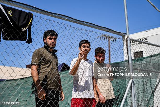 Newly arrived migrants stand in a Covid-19 quarantine area inside the migrant camp on the Greek island of Leros, on September 7, 2021. - With the...