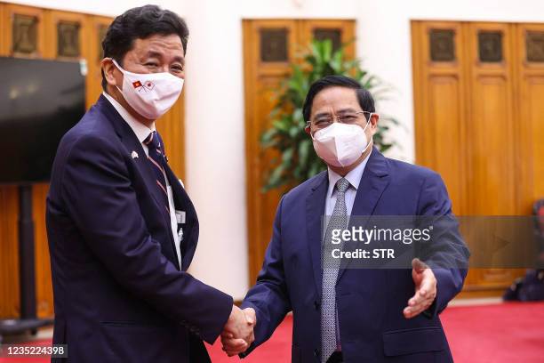 This picture taken and released by the Vietnam News Agency on September 12, 2021 shows Vietnam's Prime Minister Pham Minh Chinh shaking hands with...