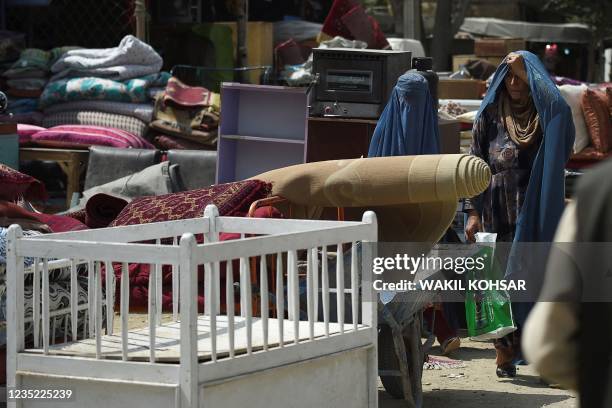 This photo taken on September 12, 2021 shows women buying secondhand household items at a market in the northwest neighbourhood of Khair Khana in...