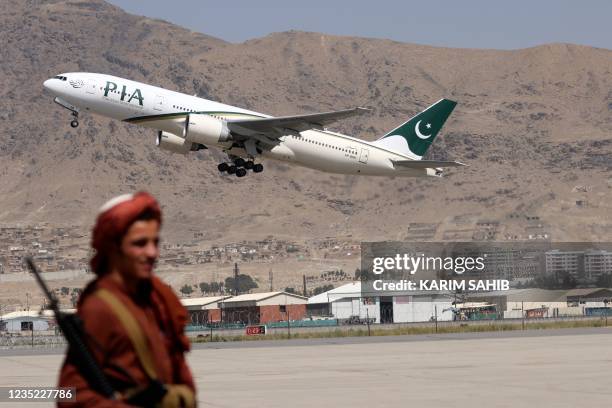 Taliban fighter stands guard as a Pakistan International Airlines plane, the first commercial international flight to land since the Taliban retook...