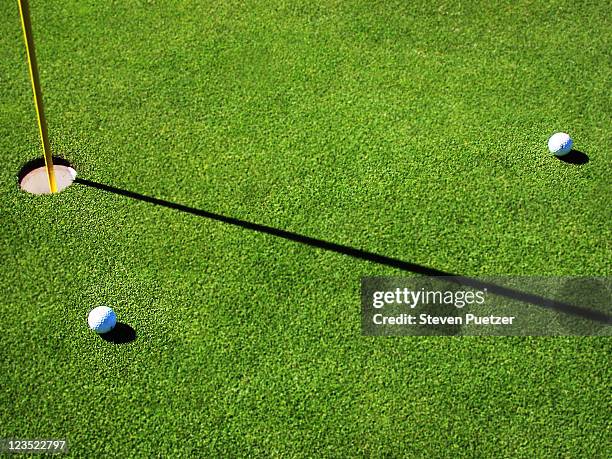 golf balls near hole - golf putting stock pictures, royalty-free photos & images