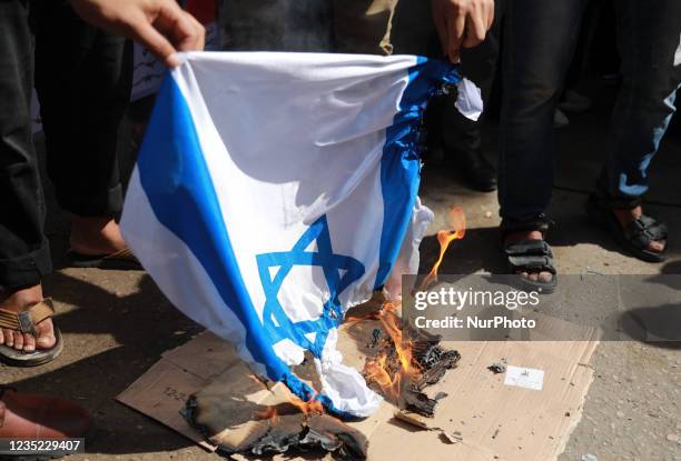 Palestinians burn an Israeli flag during a rally next the Red Cross building in Gaza City in support of more than a thousand prisoners who are in...