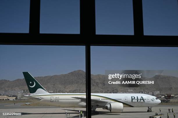 Members of ground staff stand on the tarmac beside a Pakistan International Airlines aircraft, the first commercial international flight since the...