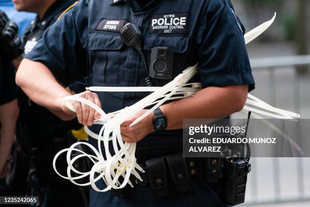 Officer gets zip ties ready handcuff protesters during a "Defund the Police" protest outside the Metropolitan Museum of Art during the MET Gala in...