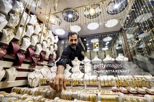 Iranian jeweller Nader Moradiyan reaches for an item inside his shop window at Tehran's Grand Bazaar in on September 14, 2021. - According to local...
