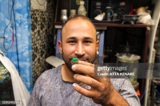 Iranian jeweller Ali Rafei poses for a photo with one of his creations in his workshop in Tehran's Grand Bazaar in on September 14, 2021. - According...