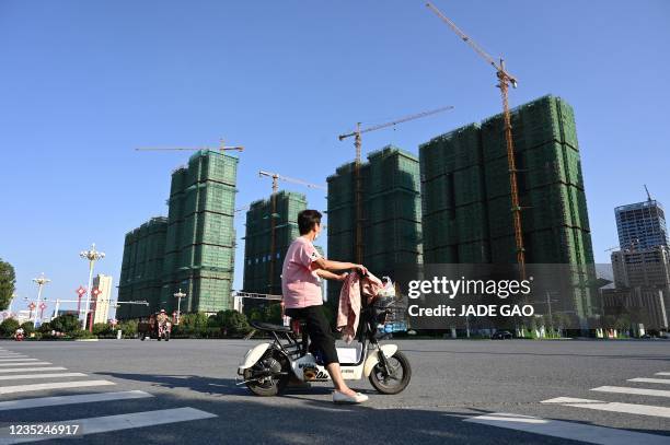 Woman rides a scooter past the construction site of an Evergrande housing complex in Zhumadian, central China's Henan province on September 14, 2021.