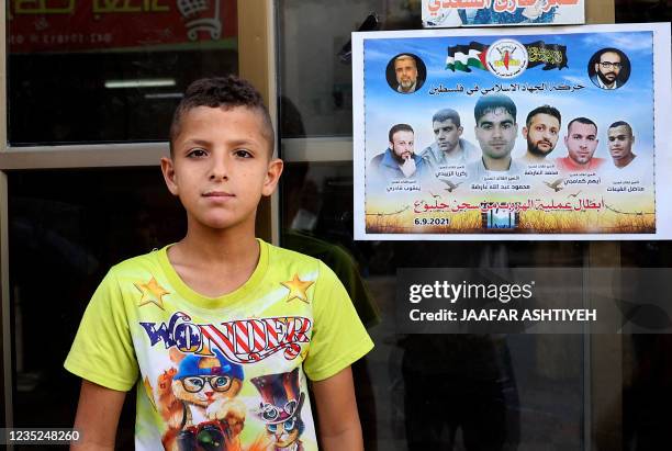 Palestinian child looks on while standing next to a poster expressing solidarity with the six Palestinian prisoners who escaped from Israel's Gilboa...