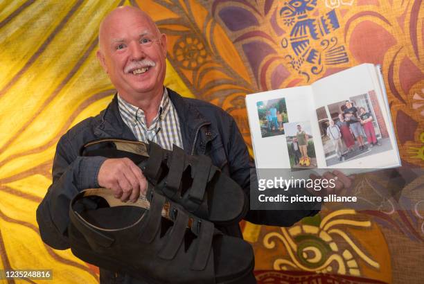 September 2021, North Rhine-Westphalia, Essen: Shoemaker Georg Wessels shows the new sandals for the biggest feet in the world and his book with...