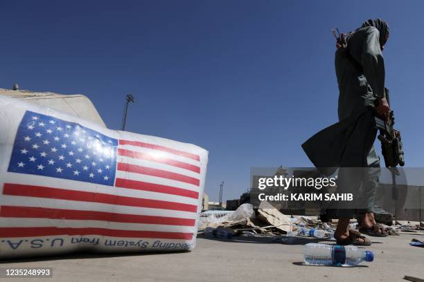 Taliban fighter walks past a US national flag at the airport in Kabul on September 14, 2021.