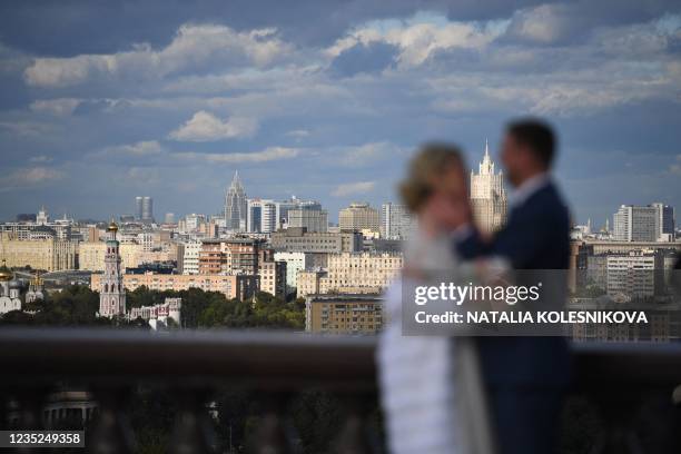 Newlyweds share a tender moment in front of the skyline at Vorobyovy Hills observation point in Moscow on September 14, 2021.