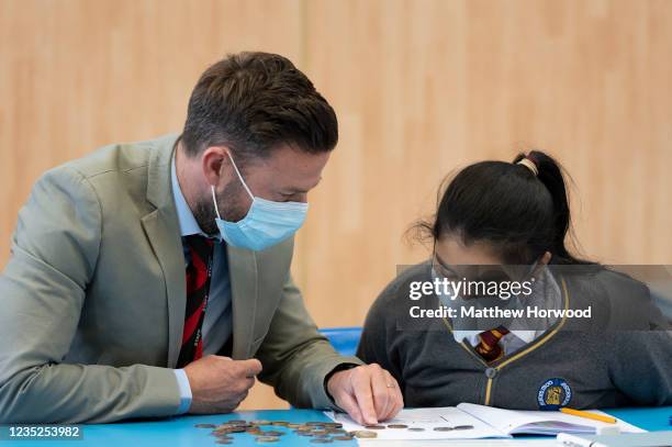 Teacher and pupil wearing face masks in a classroom at Whitchurch High School on September 14, 2021 in Cardiff, Wales. All children aged 12 to 15...