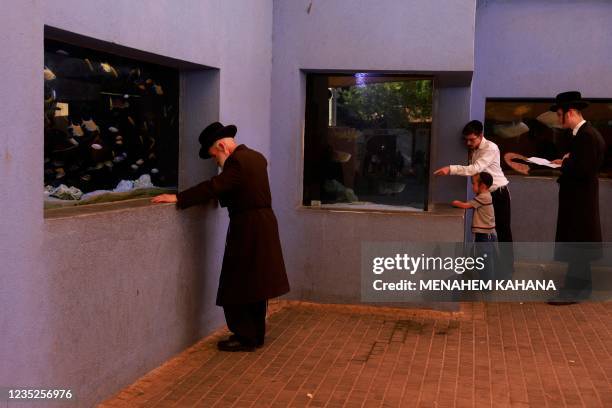 Ultra-Orthodox Jewish men pray in front of a fish aquarium at a zoo in the ultra-Orthodox Israeli city of Bnei Brak near Tel Aviv on September 14 as...