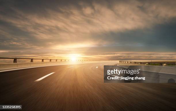 dusk colored clouds in the background, highway overpass curved approach bridge - light natural phenomenon foto e immagini stock