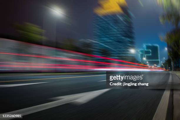 at night, wide motion blurred roads on the side of urban high-rise buildings - speed motion lines to the middle stock-fotos und bilder