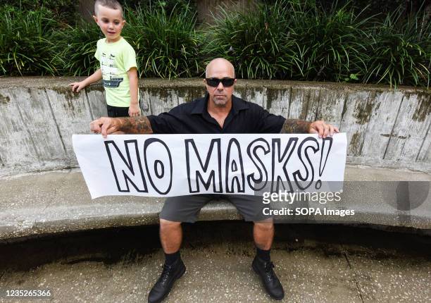 Man holds a No Masks sign outside a meeting of the Volusia County School Board in Deland. The school board voted 3-2 to modify the mandatory school...