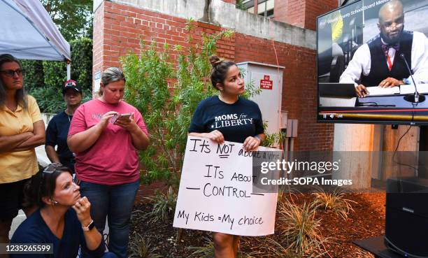 People are seen watching a video screen outside a meeting of the Volusia County School Board in Deland. The school board voted 3-2 to modify the...