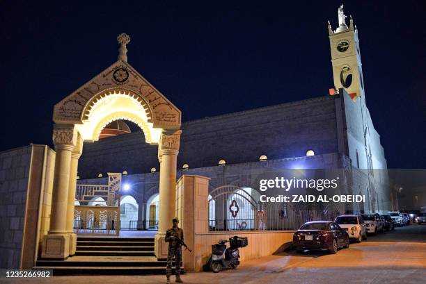 Member of security forces stands guard outside the Syriac Catholic Church of the Immaculate Conception , in Iraq's predominantly Christian town of...