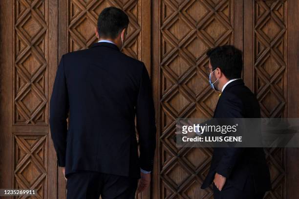 Catalan regional President Pere Aragones opens a door to Spanish Prime Minister Pedro Sanchez prior to holding a meeting at the Generalitat palace in...