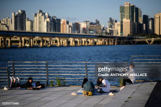 Man throws a paper airplane as he and friends relax along the Han River in Seoul on September 15, 2021.